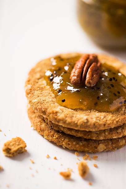 Stack of oatmeal cookies topped with a glossy fruit jam and a pecan nut