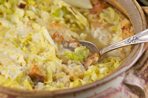A close-up view of a creamy cabbage casserole with a golden crust, served in a ceramic dish with a spoon.