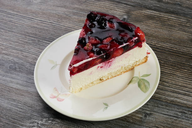 A slice of berry-topped cheesecake on a decorative plate.