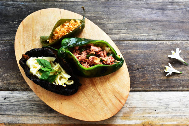 Three stuffed peppers on a wooden platter, showcasing colorful fillings.