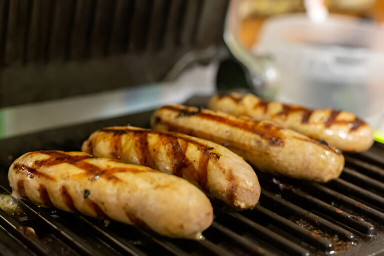 Grilled sausages cooking on a barbecue grill.