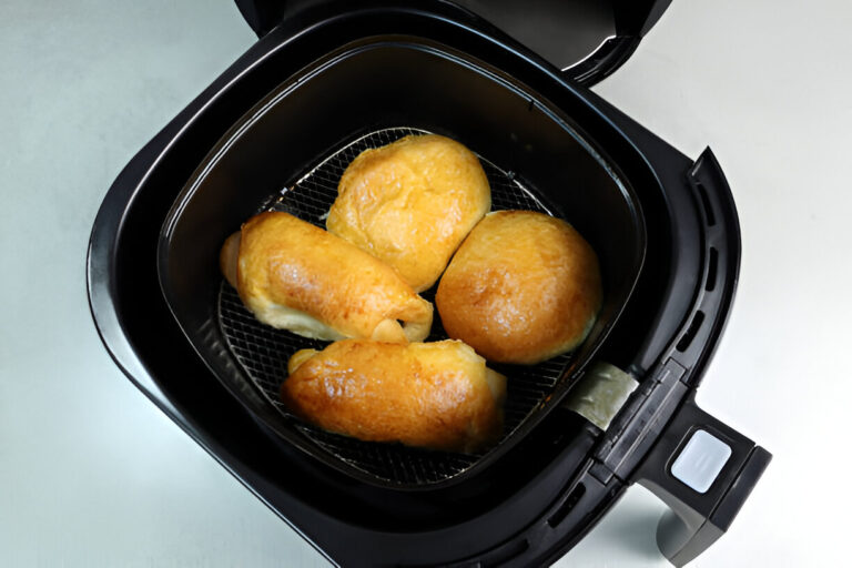 Freshly cooked golden brown rolls in an air fryer basket.