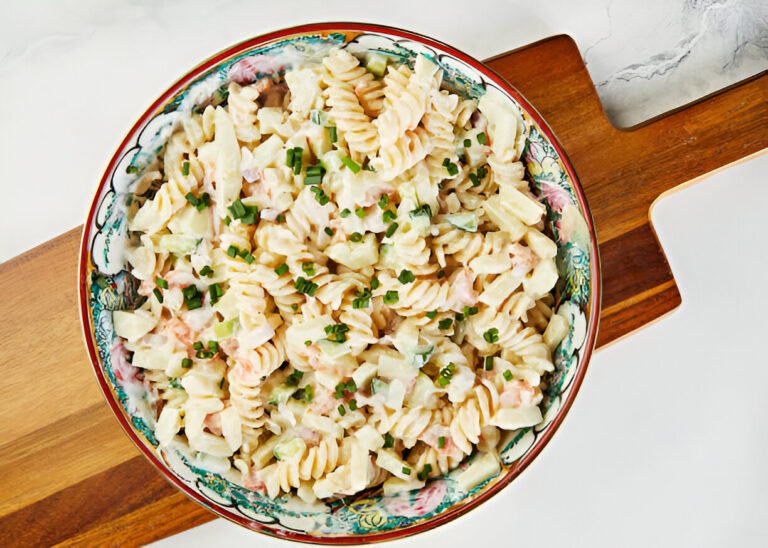 A bowl of creamy pasta salad with rotini noodles, diced vegetables, and chopped chives.
