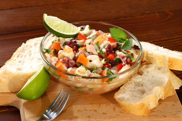 A bowl of seafood salad topped with lime slices, accompanied by slices of bread on a wooden board.