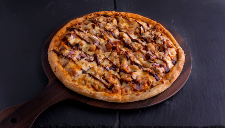 Delicious pizza with BBQ sauce and toppings served on a wooden platter