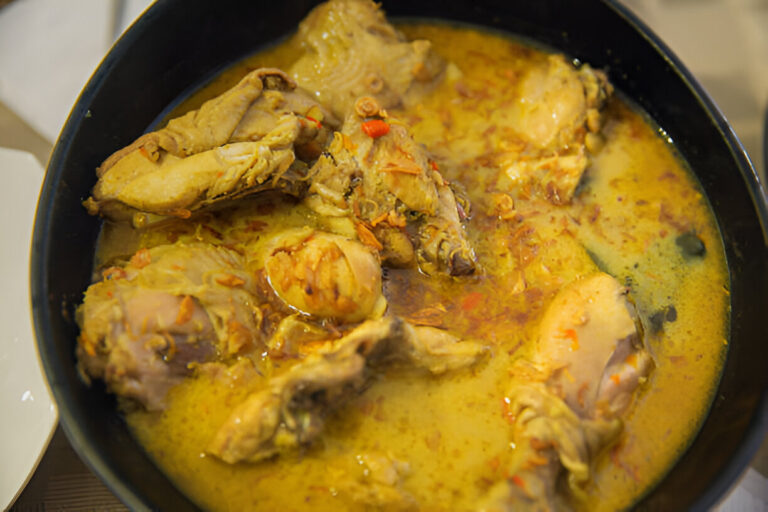 A bowl of chicken curry with a yellow sauce.