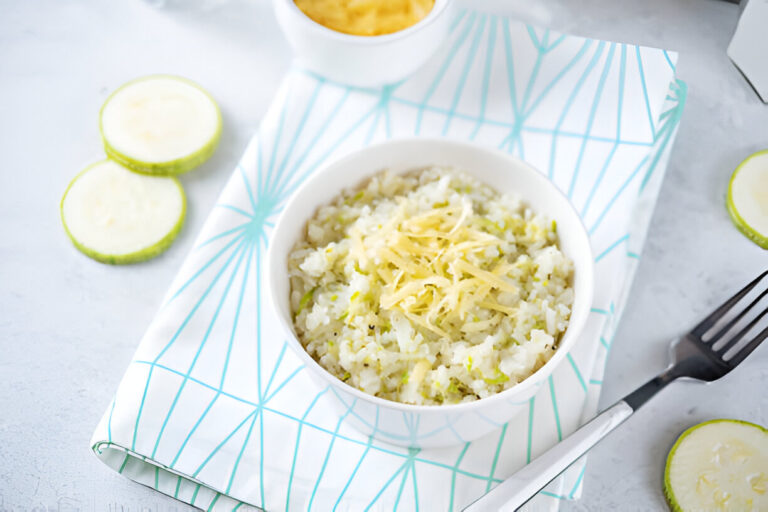 Bowl of rice topped with shredded cheese on a patterned napkin, with lime slices on the side.