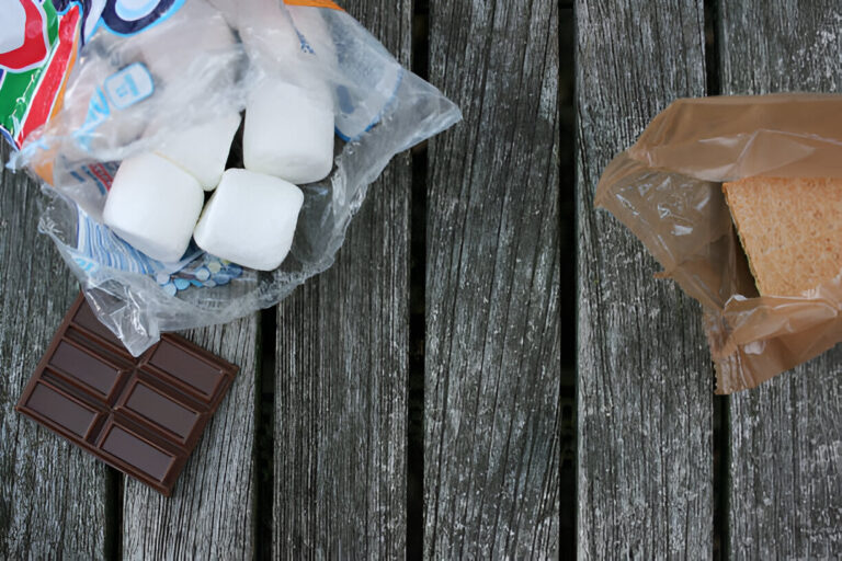 A top-down view of s'mores ingredients including marshmallows, chocolate, and graham crackers on a wooden surface.