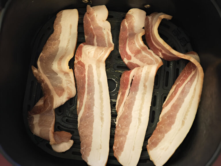 Slices of bacon arranged in an air fryer basket.