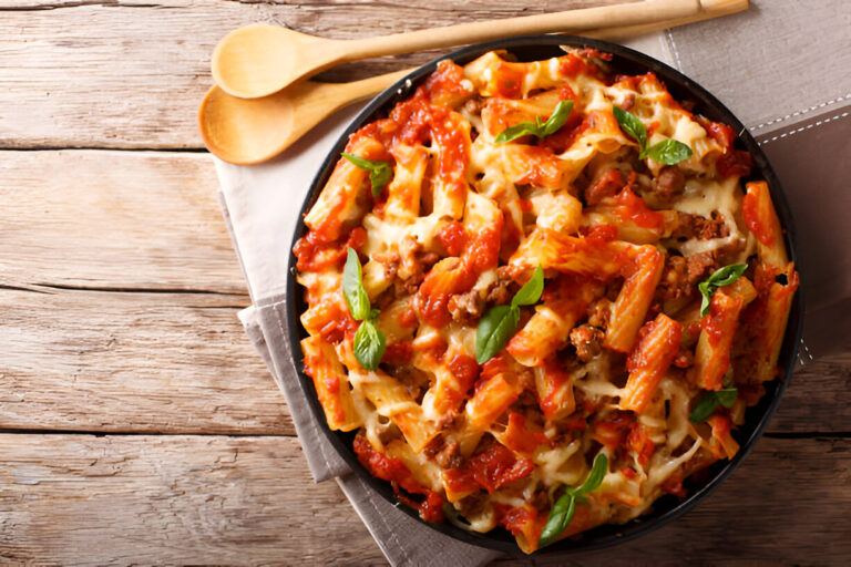 A delicious serving of baked pasta with meat sauce and cheese, garnished with fresh basil leaves.