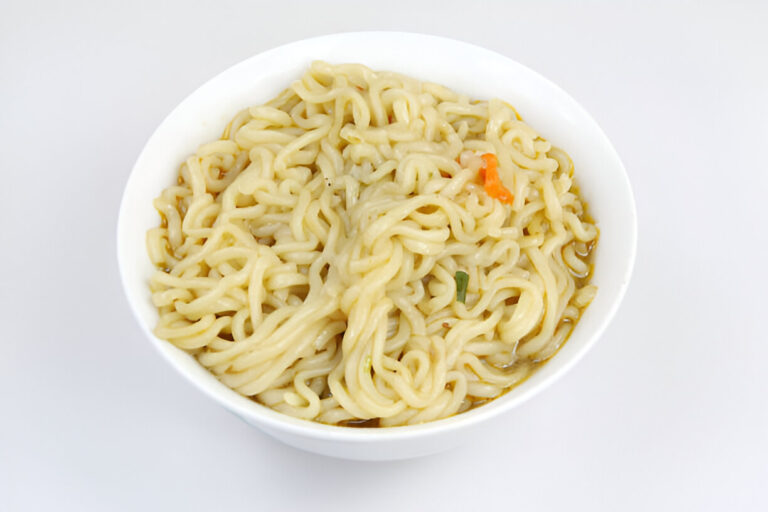 A bowl of cooked instant noodles with a hint of vegetables and broth.