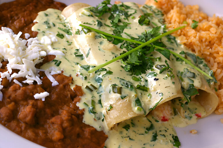 Plate of enchiladas topped with green sauce, cilantro, and accompanied by rice and refried beans.