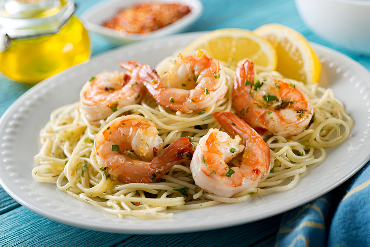A plate of shrimp scampi with pasta, garnished with herbs and lemon slices.
