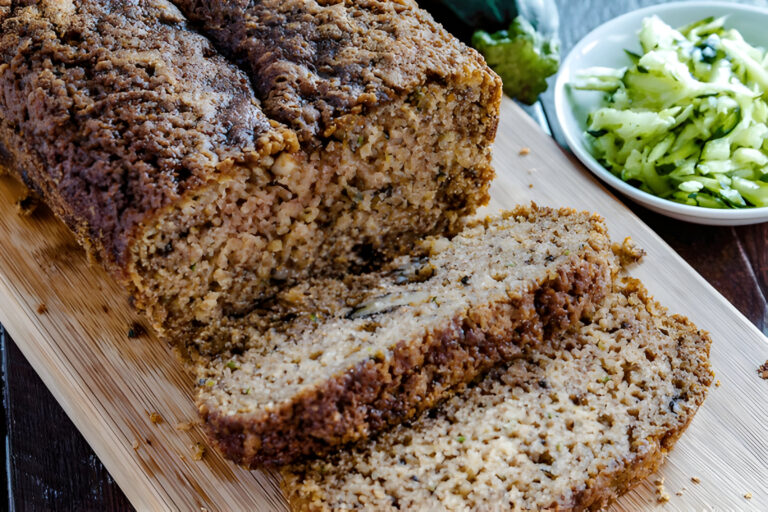 Sliced loaf of savory meat or veggie dish on a wooden cutting board with a side of shredded cucumber salad.